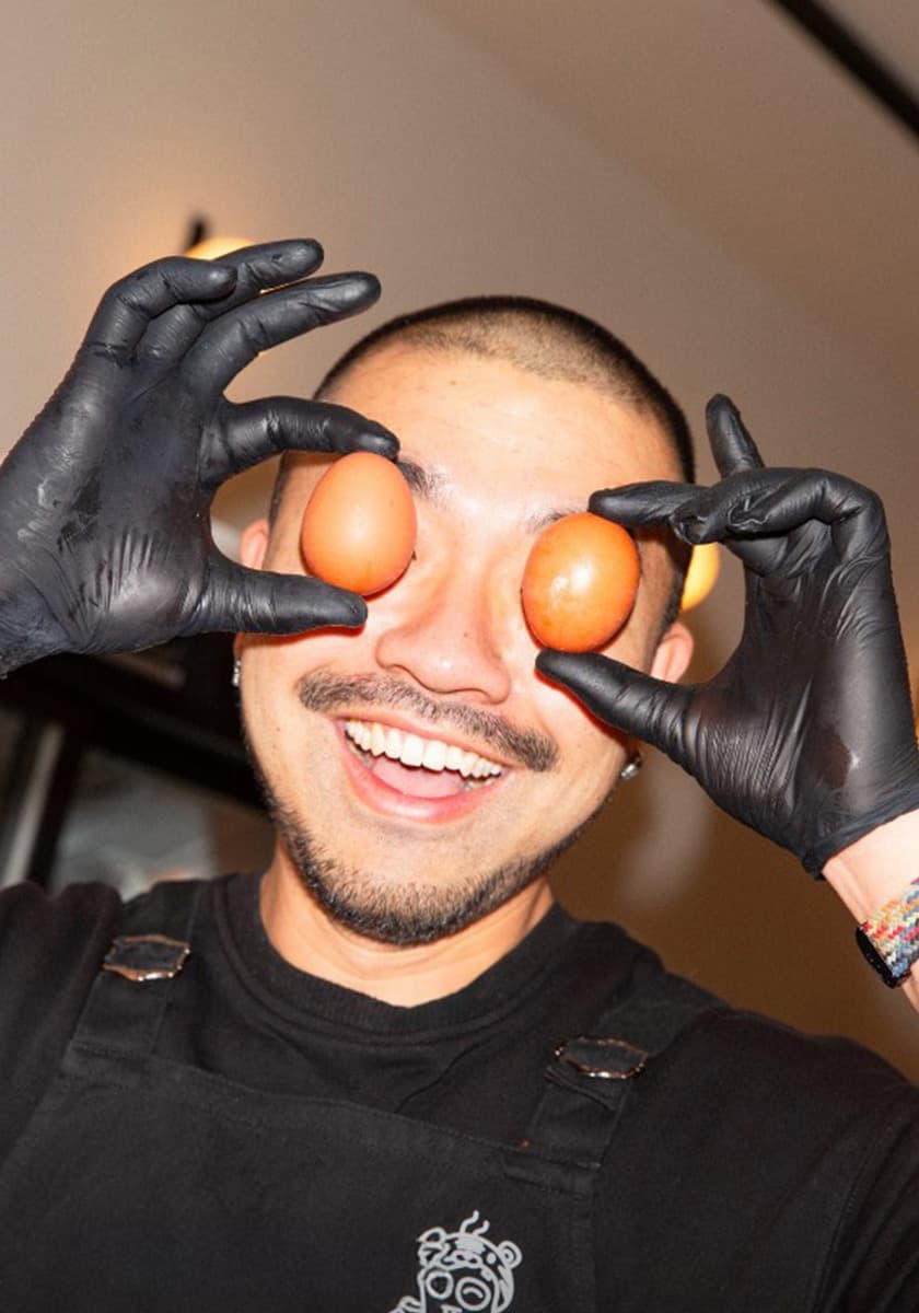 Porträtslider-Bild: junger Koch mit schwarzen Handschuhen und Früchten vor den Augen